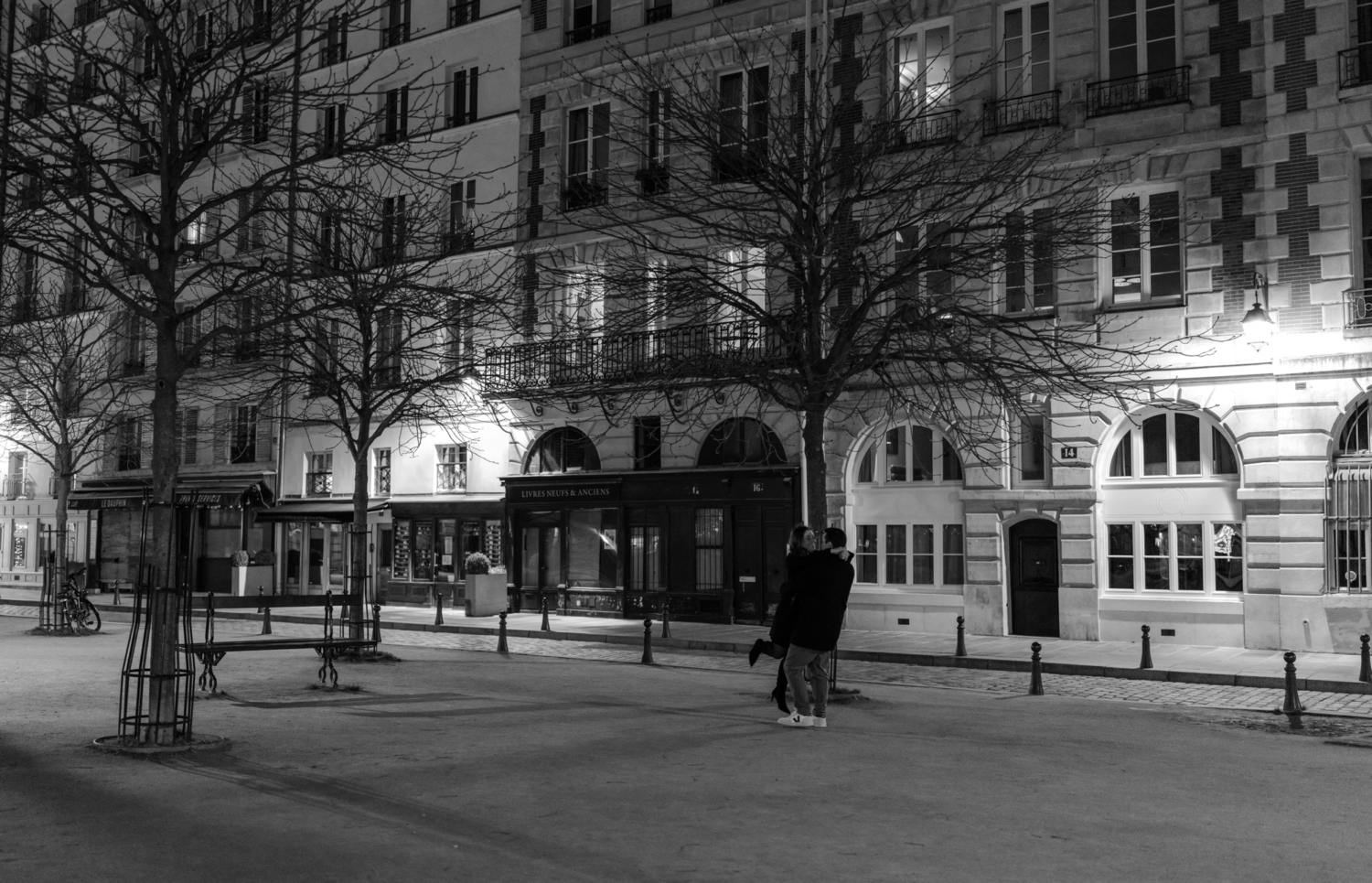 man lifts woman in air during engagement photoshoot at night in paris