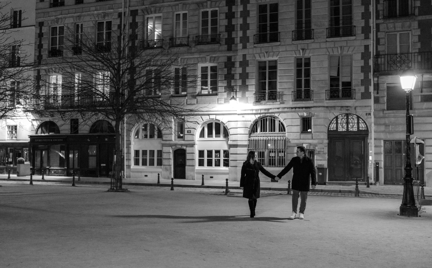 engaged couple walk hand in hand at place dauphine in paris