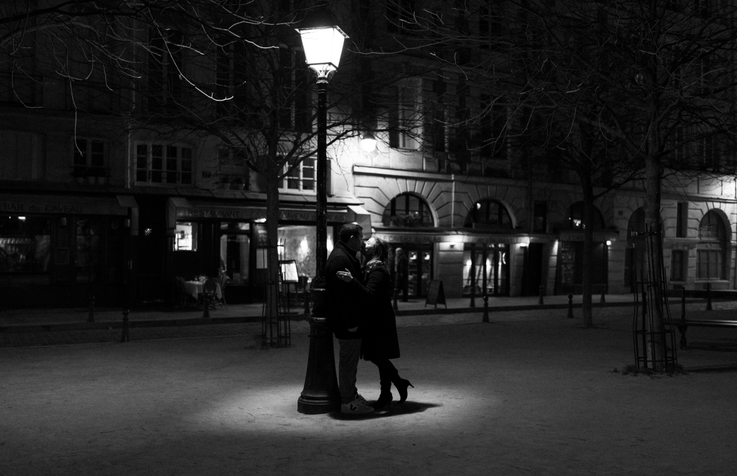 engaged couple kiss under streetlamp at night in paris