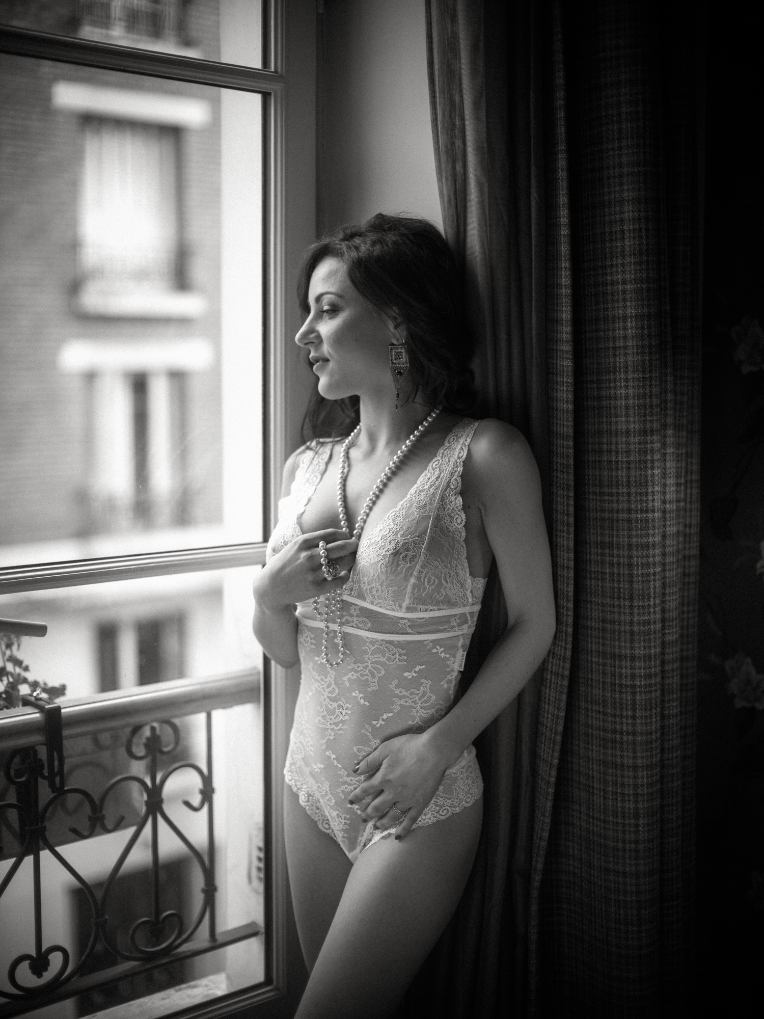 woman in lingerie looks out window during boudoir photoshoot in paris