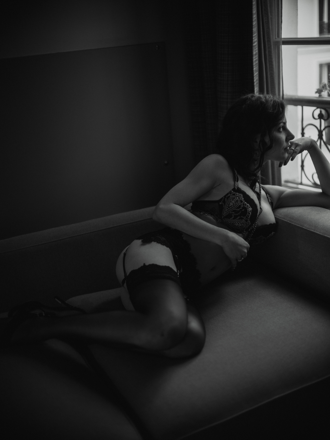 wonan wearing lingerie looks out window during boudoir photoshoot in paris