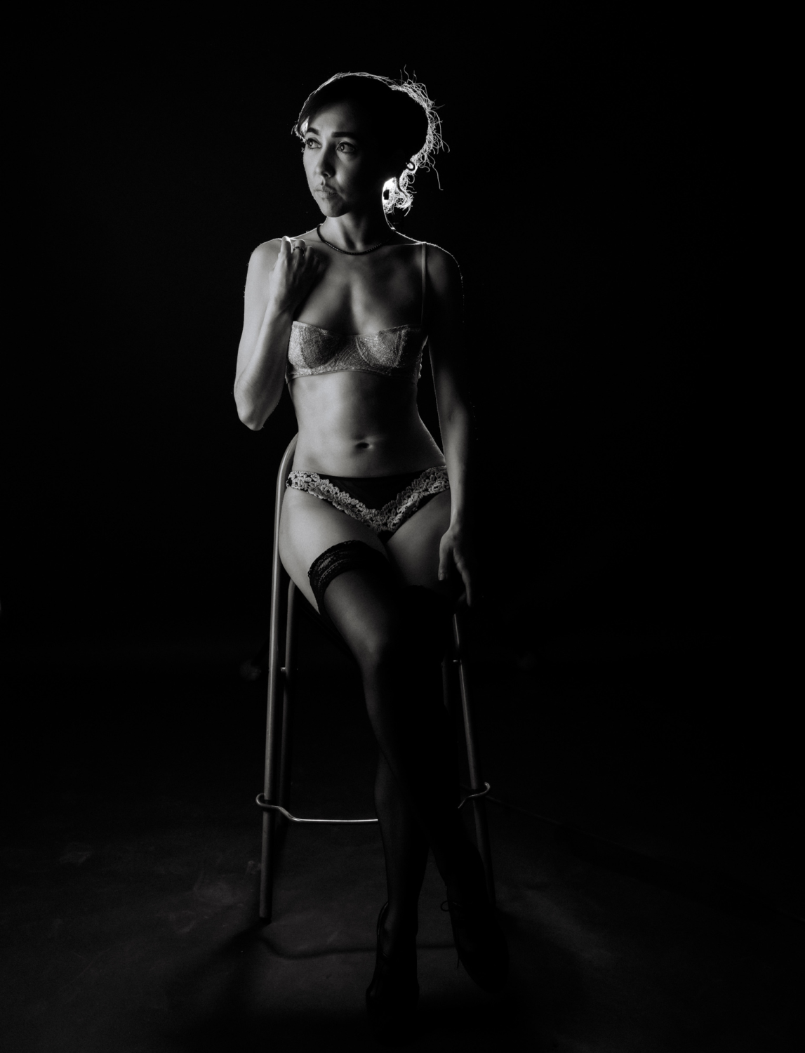 woman sits on chair in lingerie for boudoir photoshoot in paris