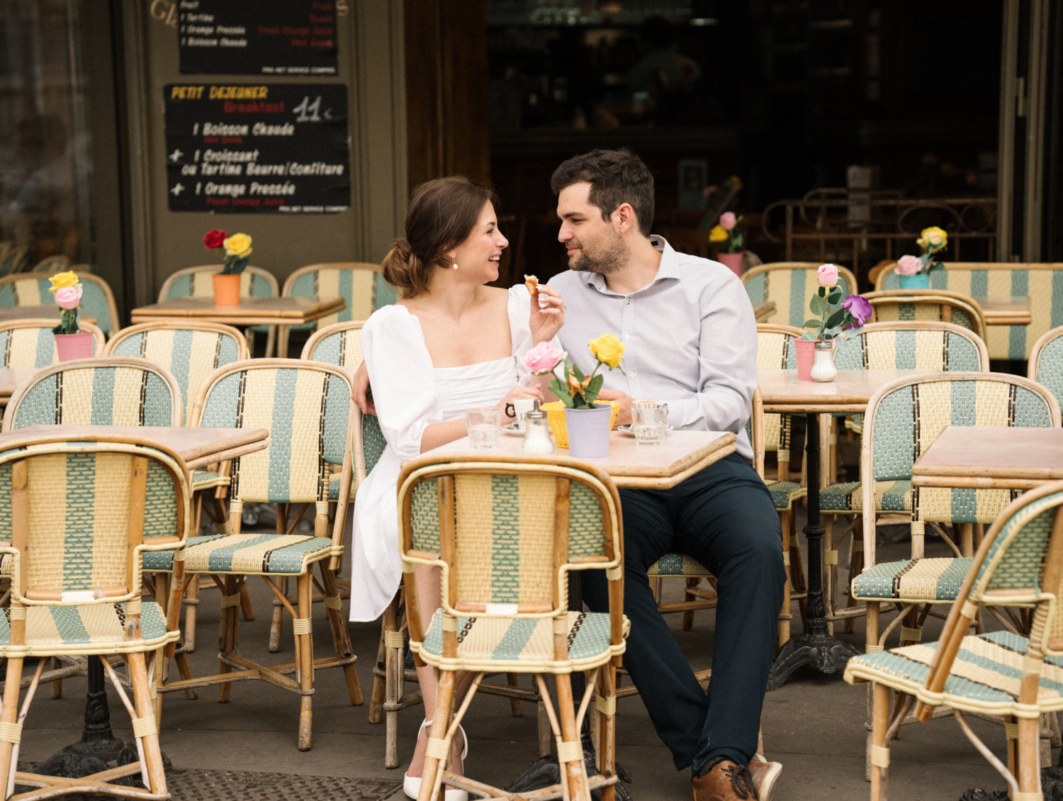 engaged couple share a croissant at cafe in paris