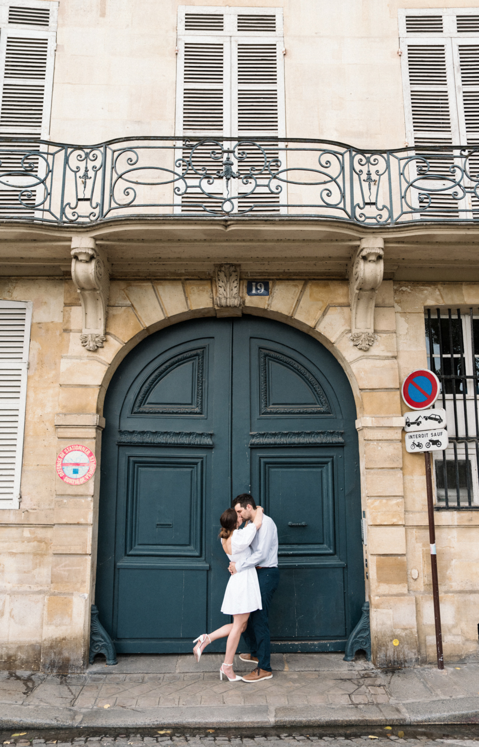 engaged couple share passionate kiss in front of green door in paris