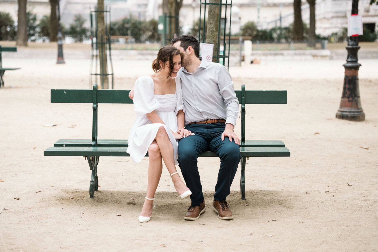 engaged couple sit on bench in paris park