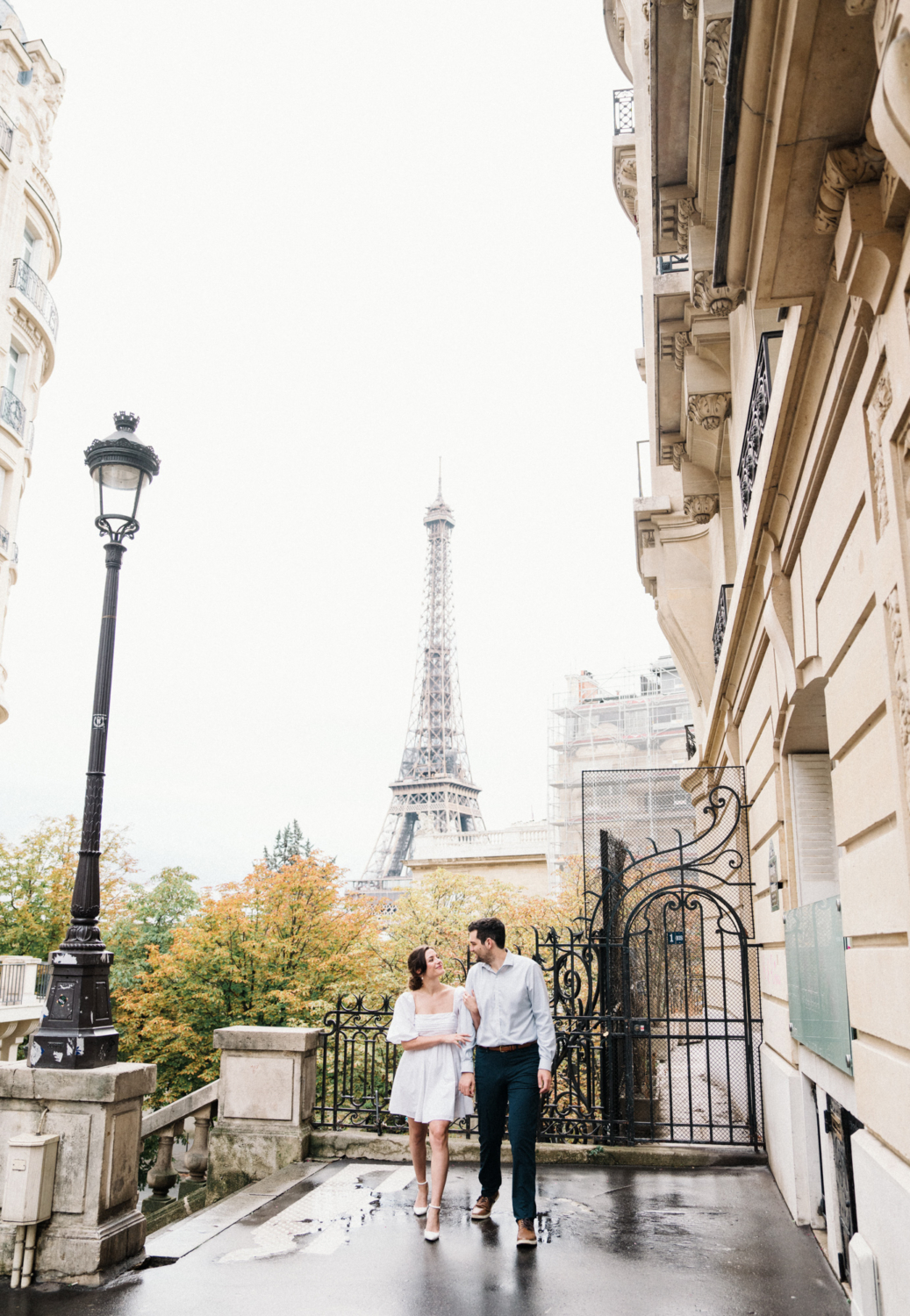 engaged couple walk and laugh with view of eiffel tower