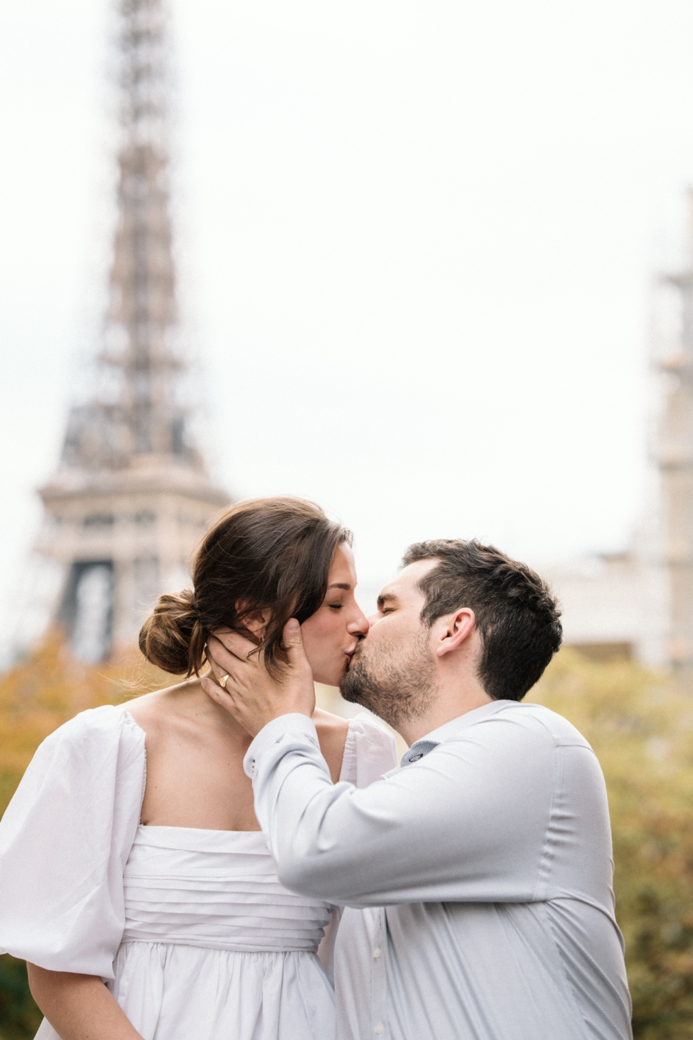 engaged couple kiss at eiffel tower in paris