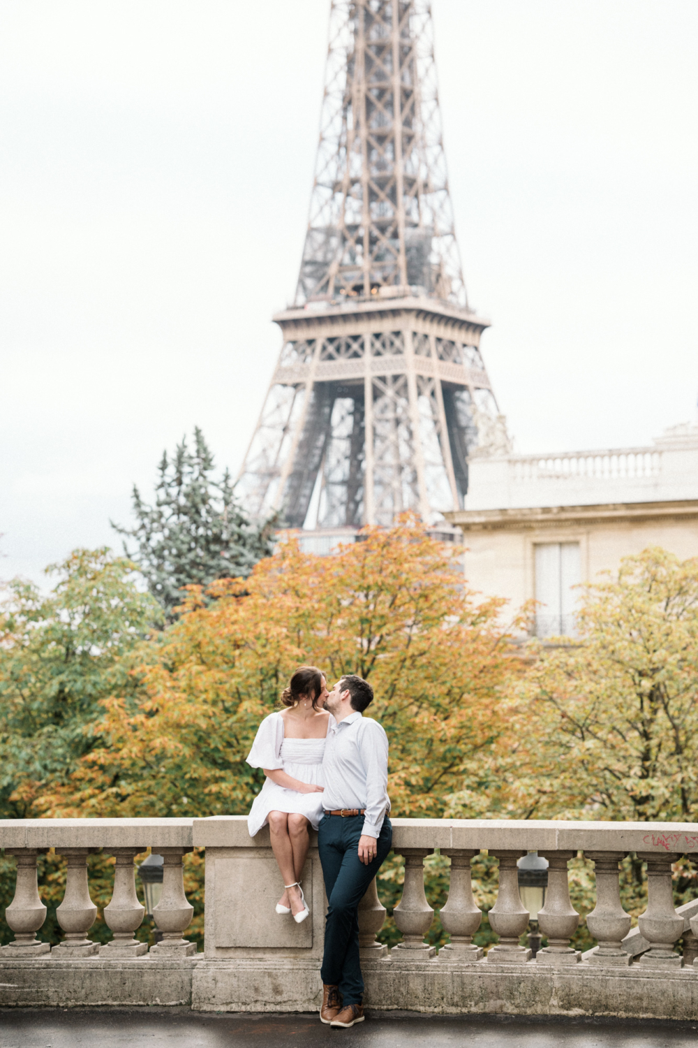 engaged couple kiss with view of eiffel tower in paris