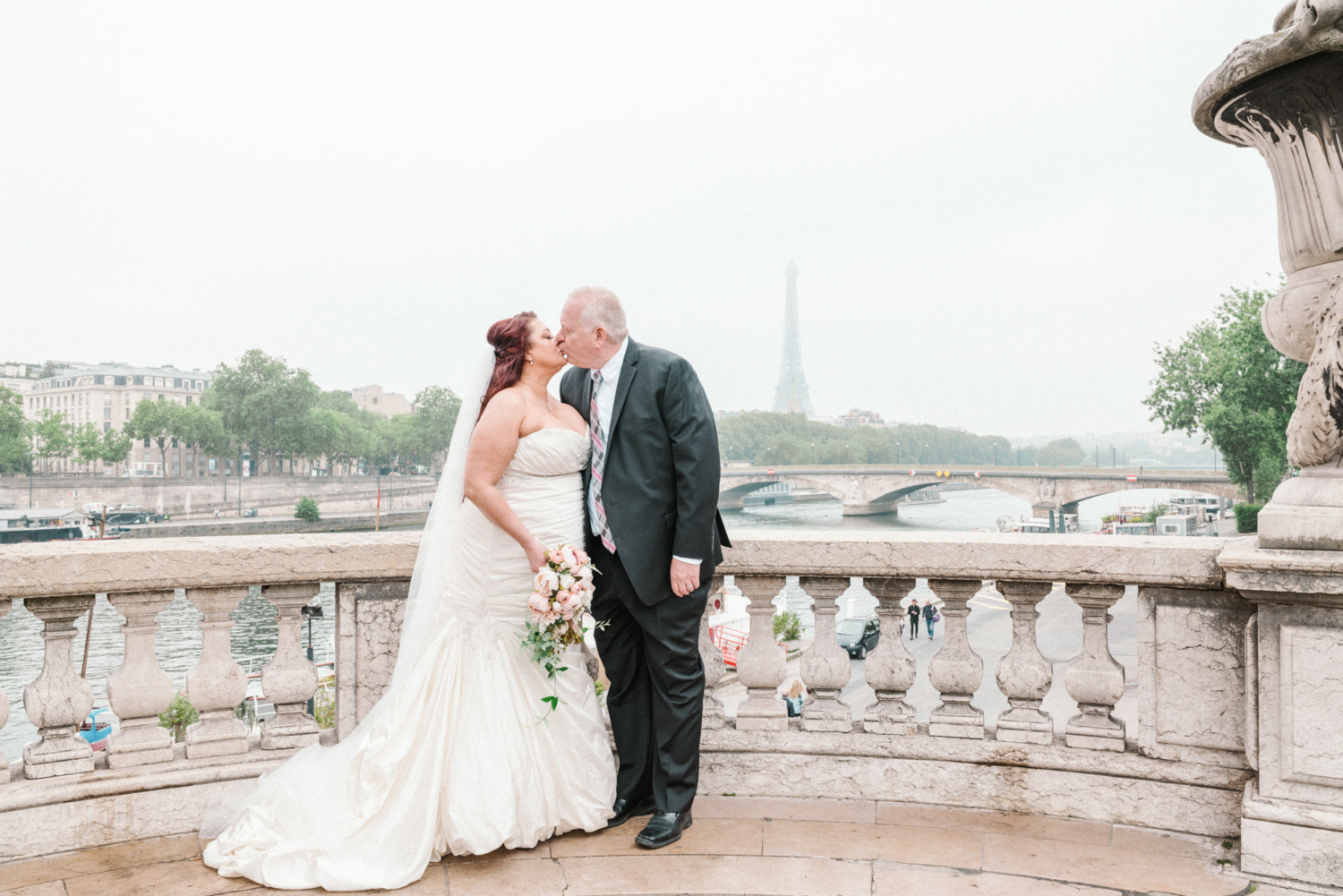 bride and groom kiss on pont alexandre with view of the eiffel tower