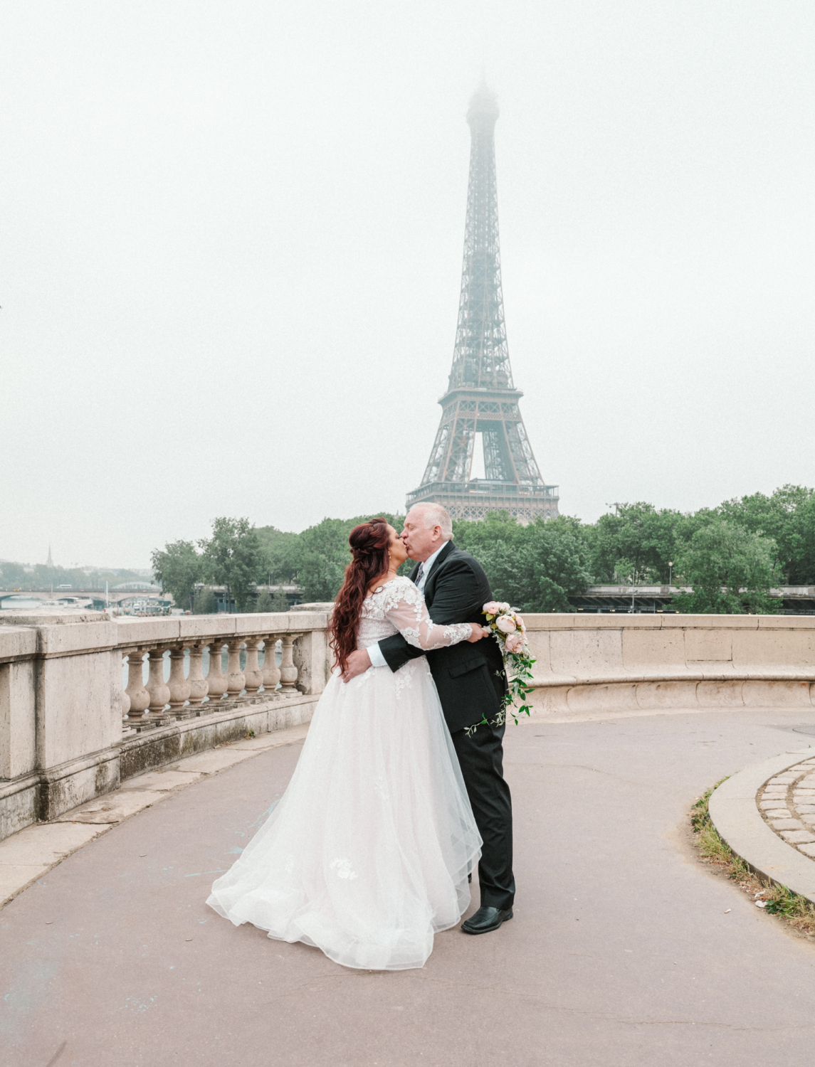 bride and groom hug and kiss with view of eiffel tower paris