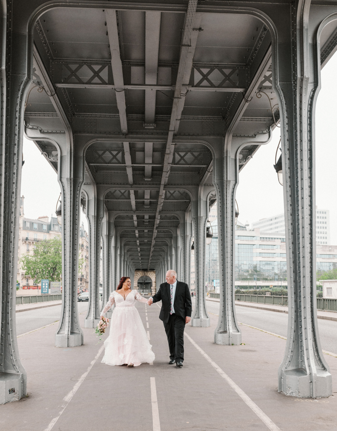 bride and groom walk and laugh at bir hakeim bridge in paris