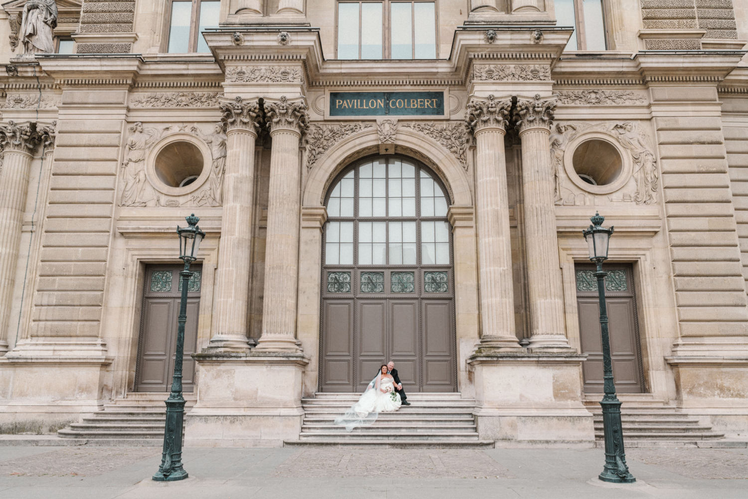 bride and groom pose on the stairs at the louvre in paris