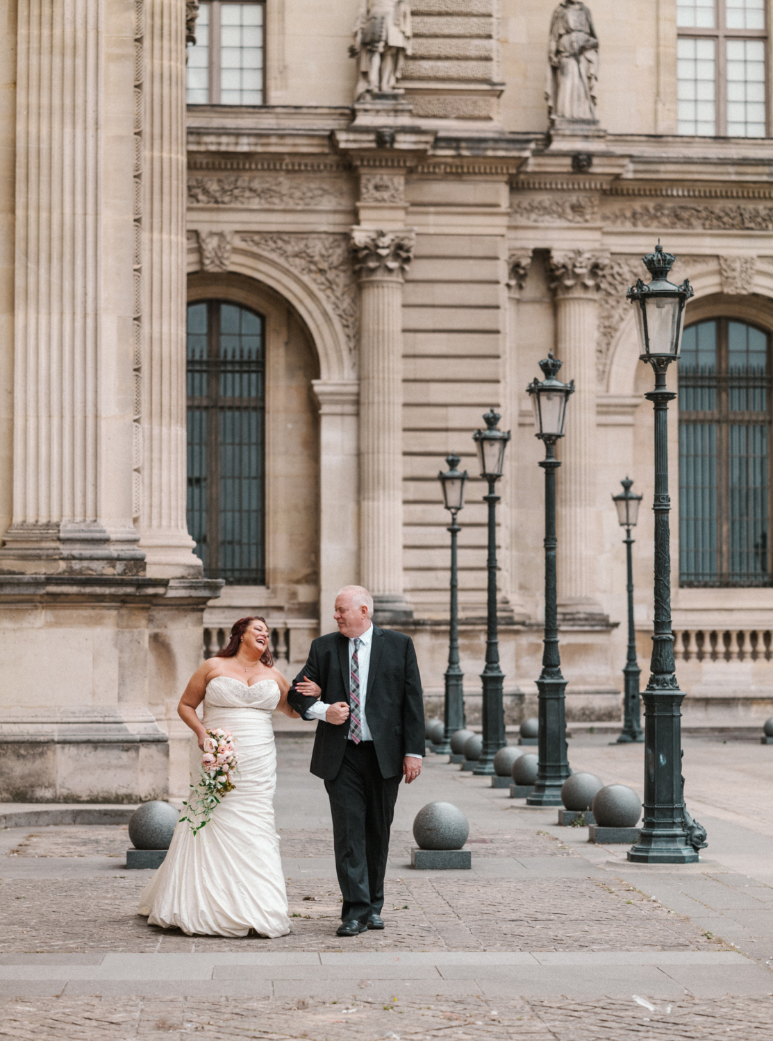 bride and groom share a laugh at the louvre in paris