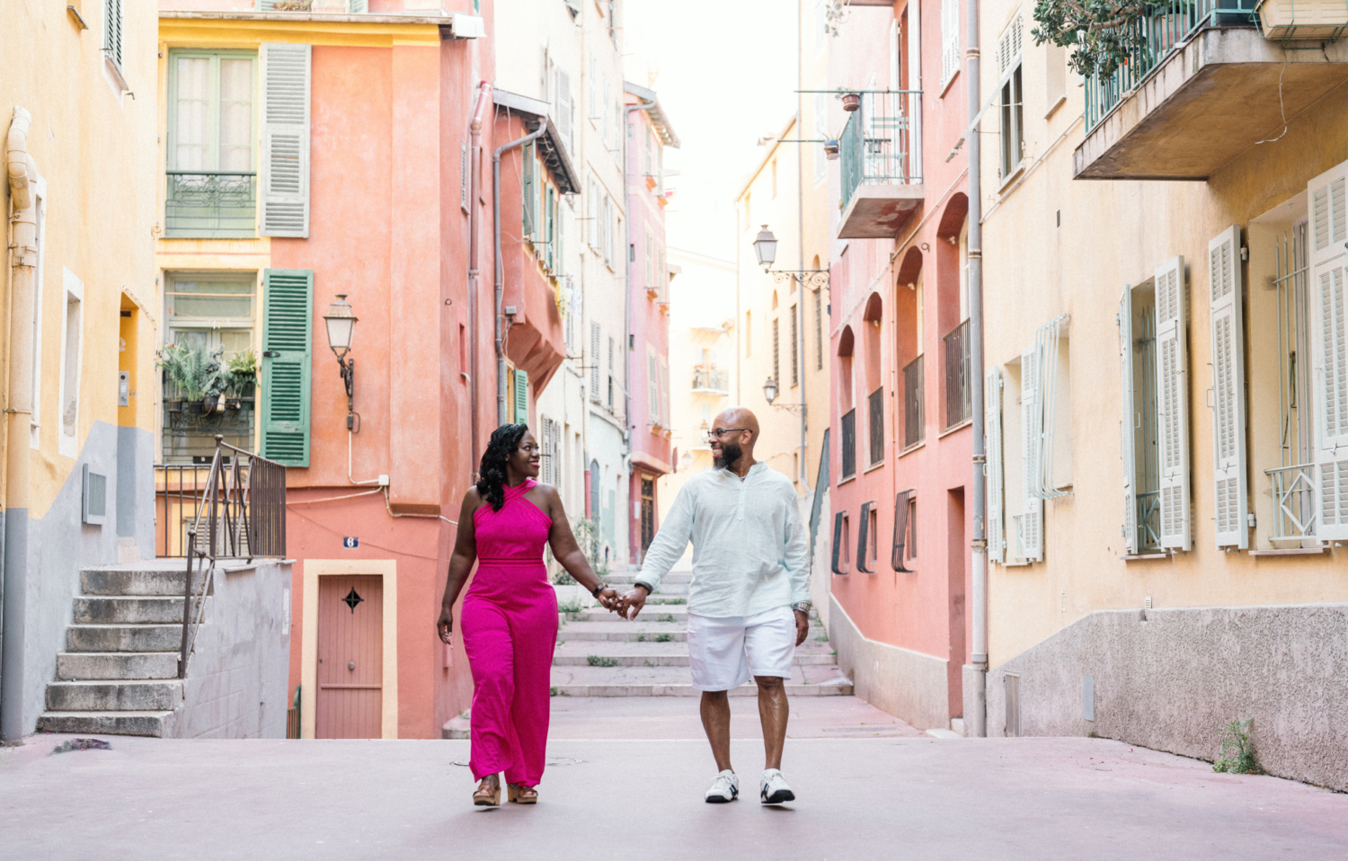 couple walk holding hands surrounded by colorful buildings