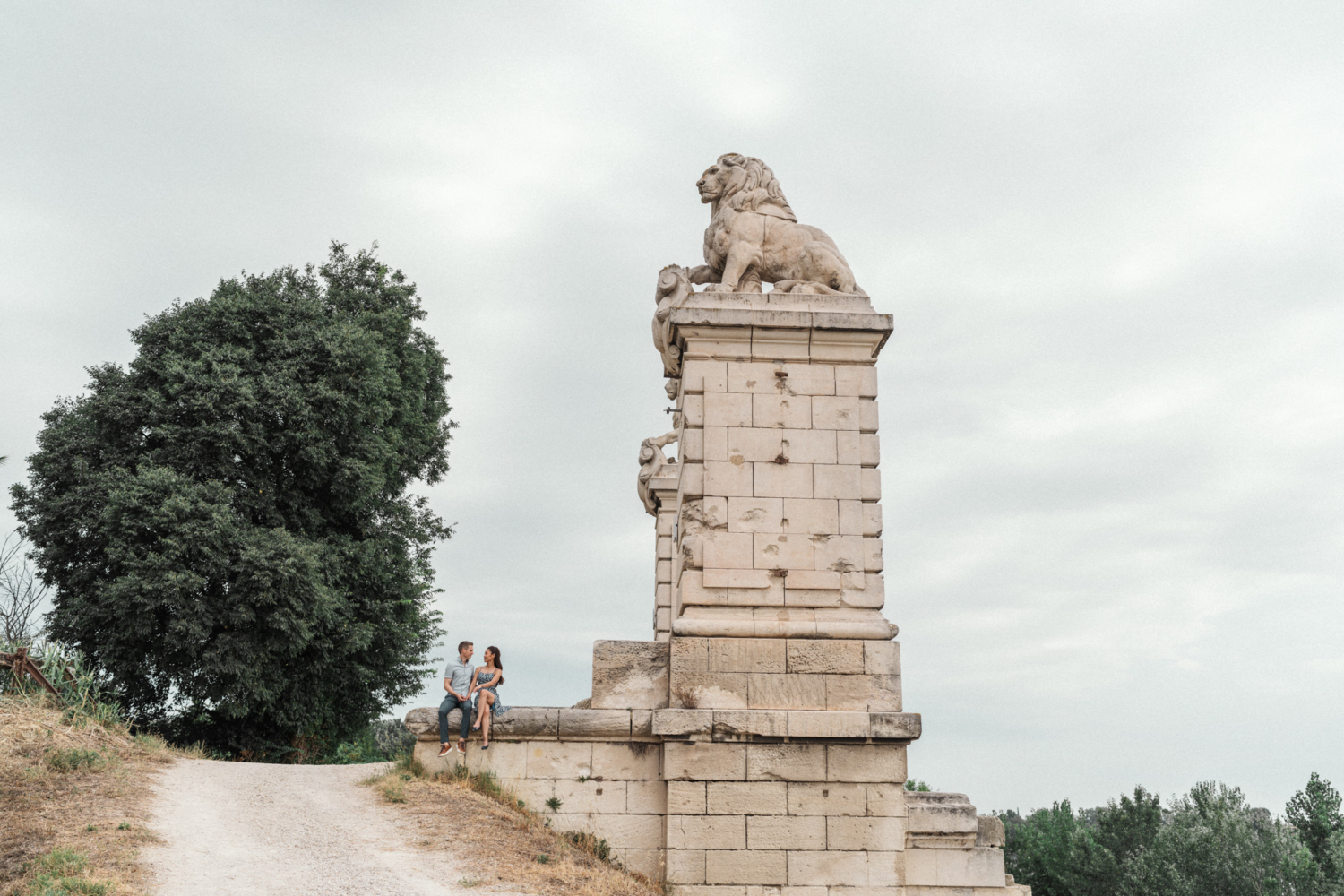couple sit on lion bridge in arles, france