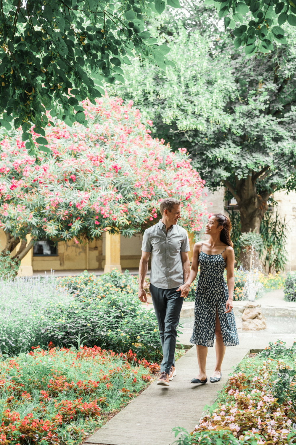 engaged couple hold hands walking through garden