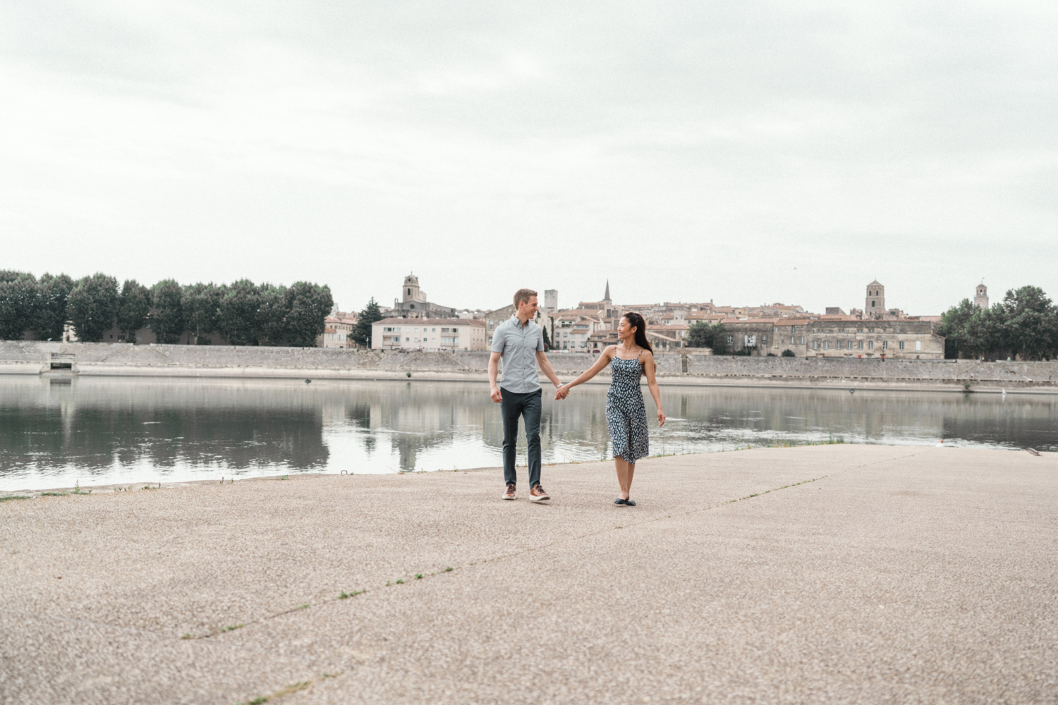 couple walk holding hands with medieval city in background