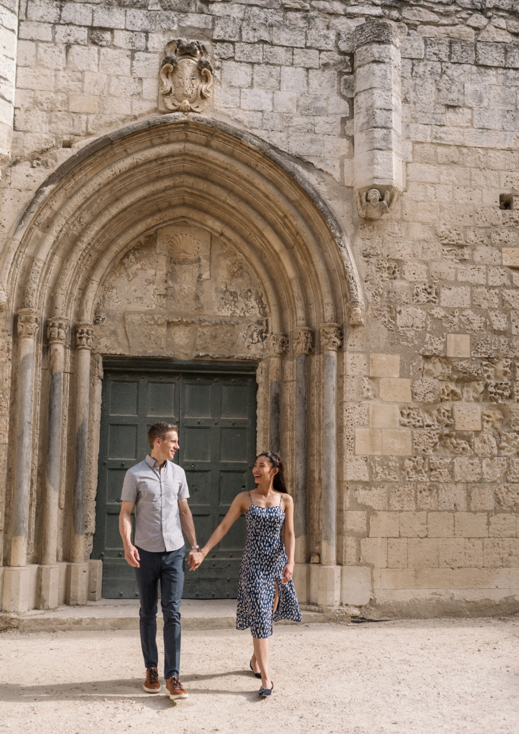 couple walk hand in hand at old church