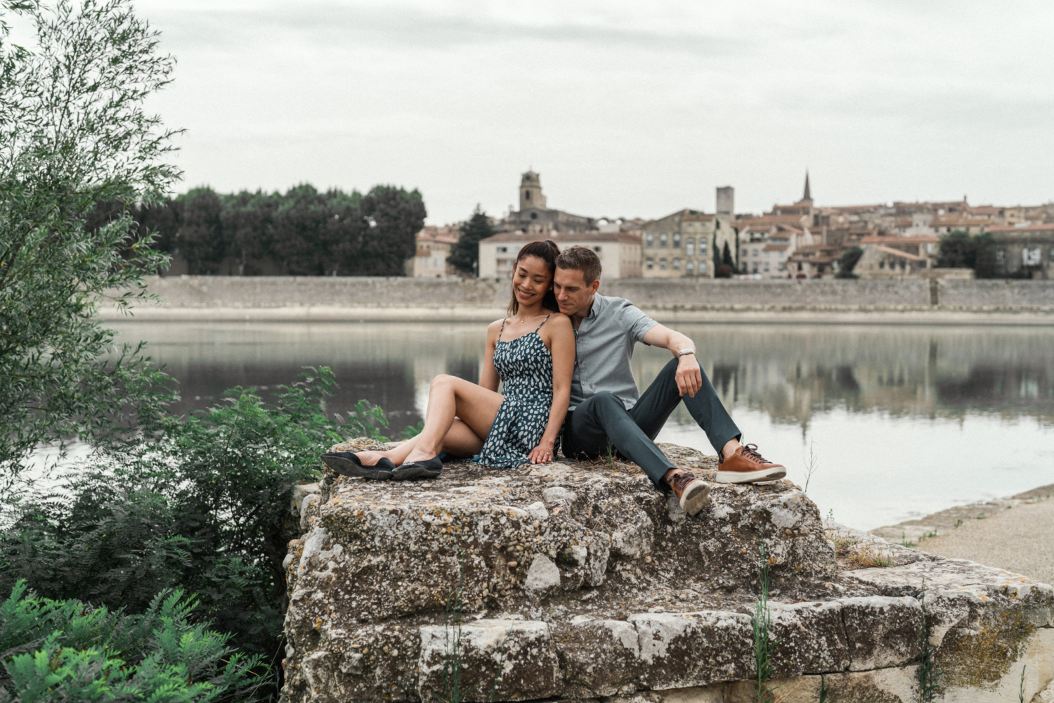 couple sit on rock with old town behind them