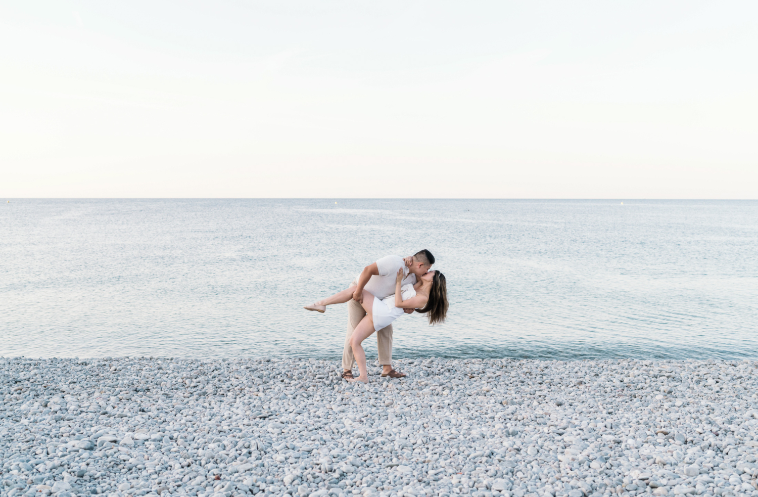 husband dips wife and kisses her on beach in nice france