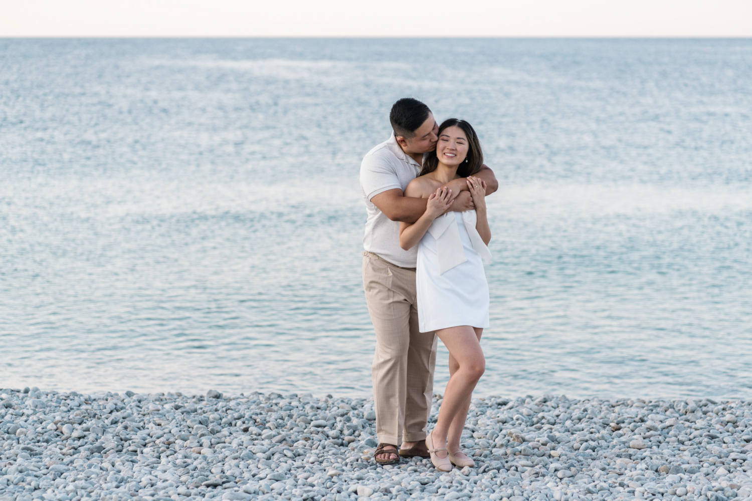 husband embraces wife next to sea in nice france