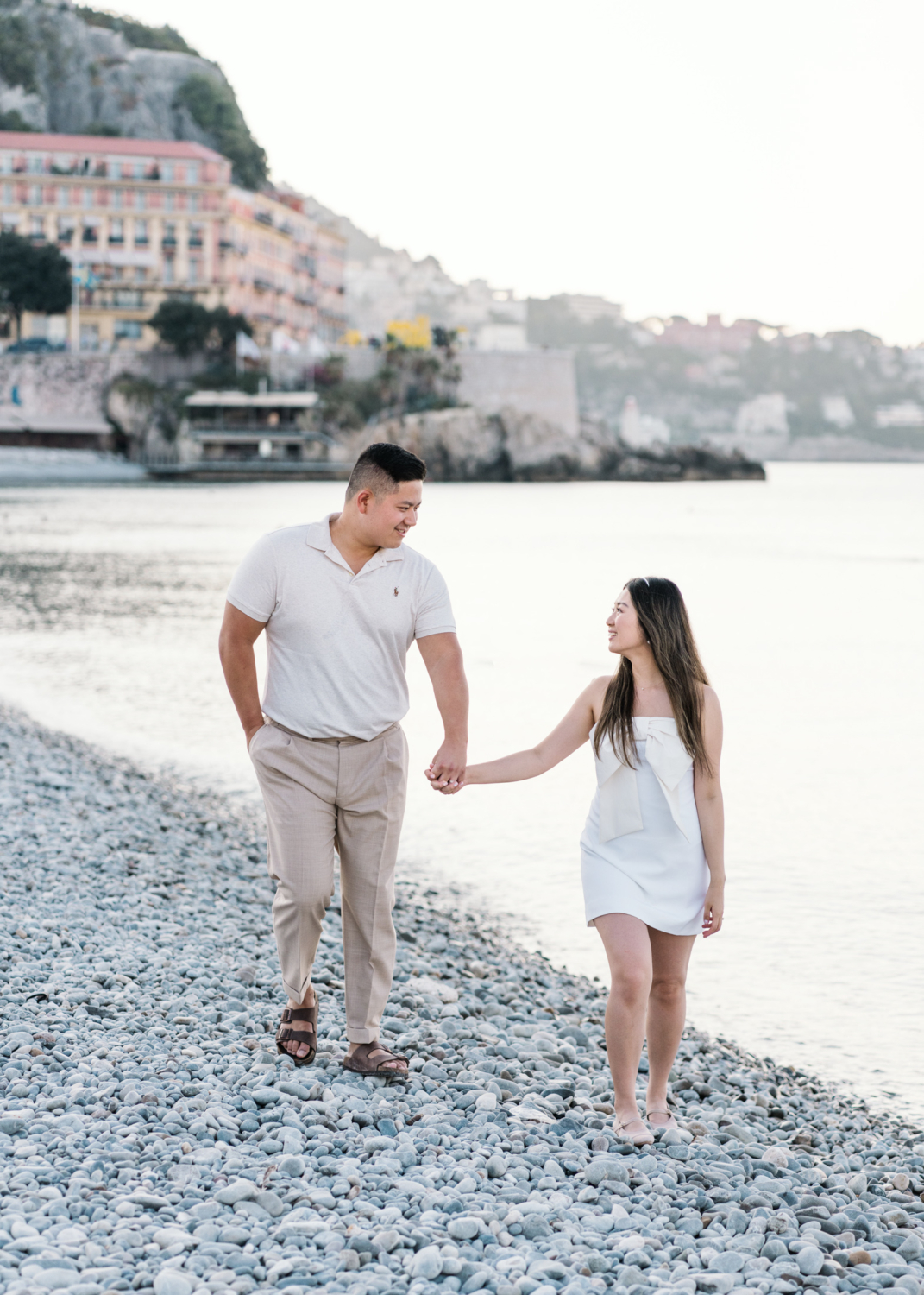 newlywed couple walk hand in hand on stone beach in nice france