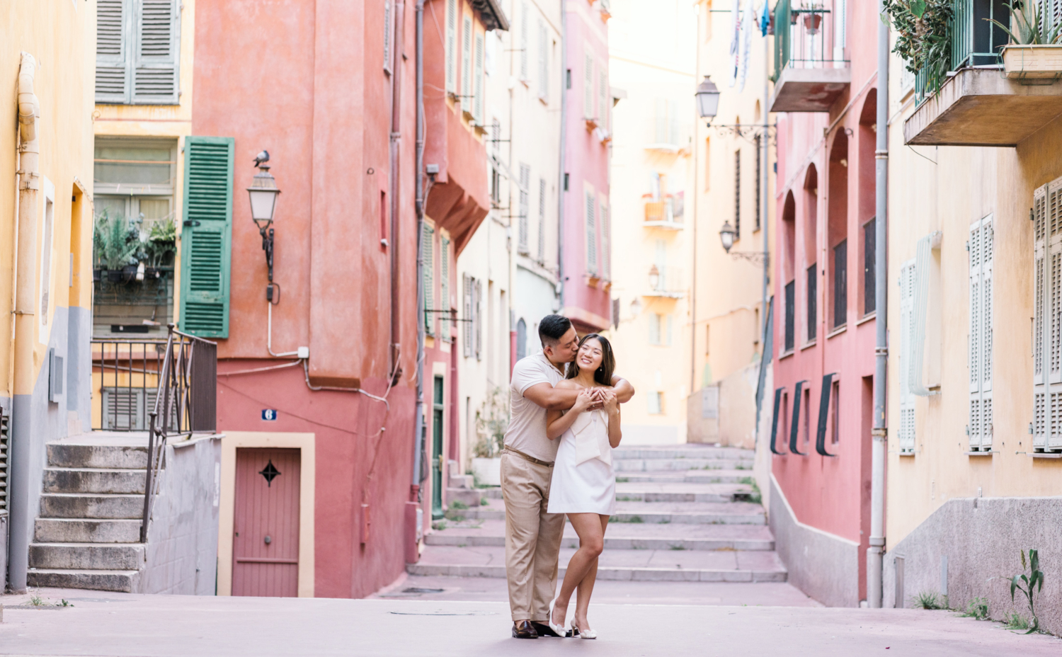 man embraces woman and kisses her on cheek in old town nice