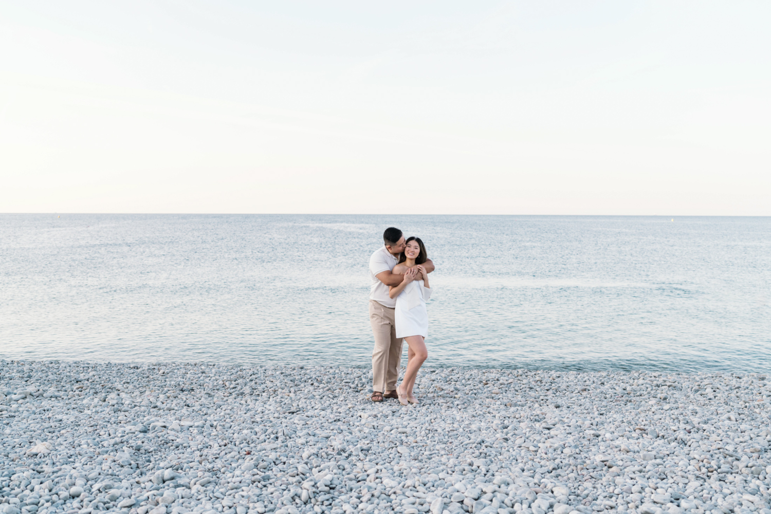 man embraces woman on beach in nice france next to sea