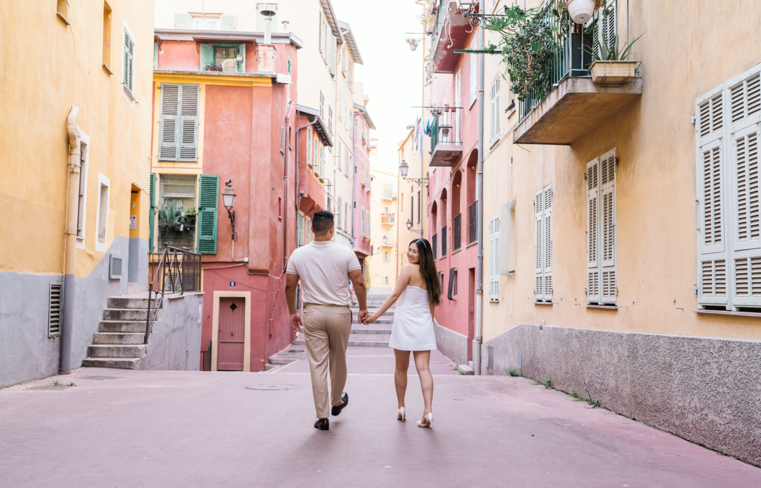 woman smiles at camera holding hands with man in nice france