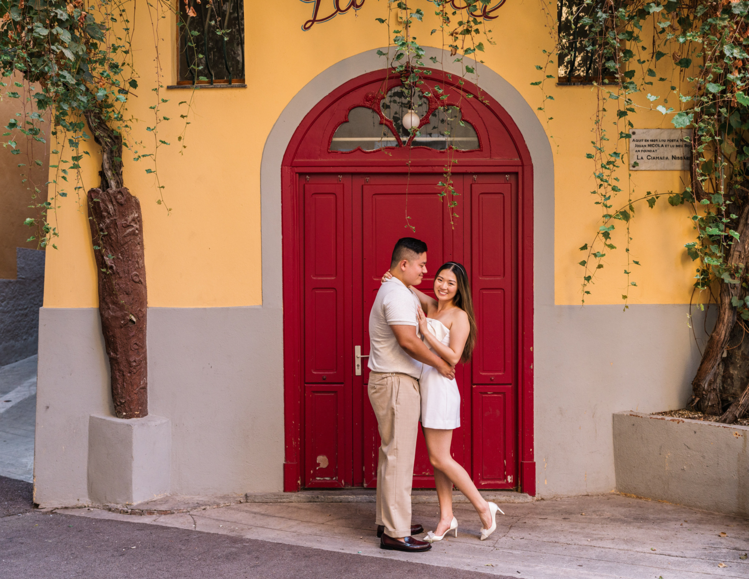 cute couple pose in front of red door in nice france