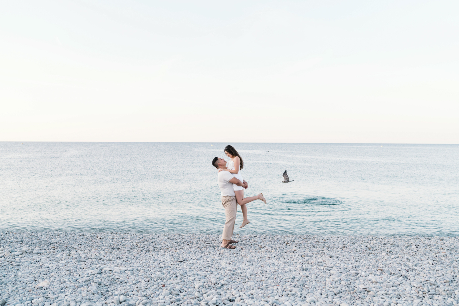 man lifts woman at sea as bird flies by in nice france