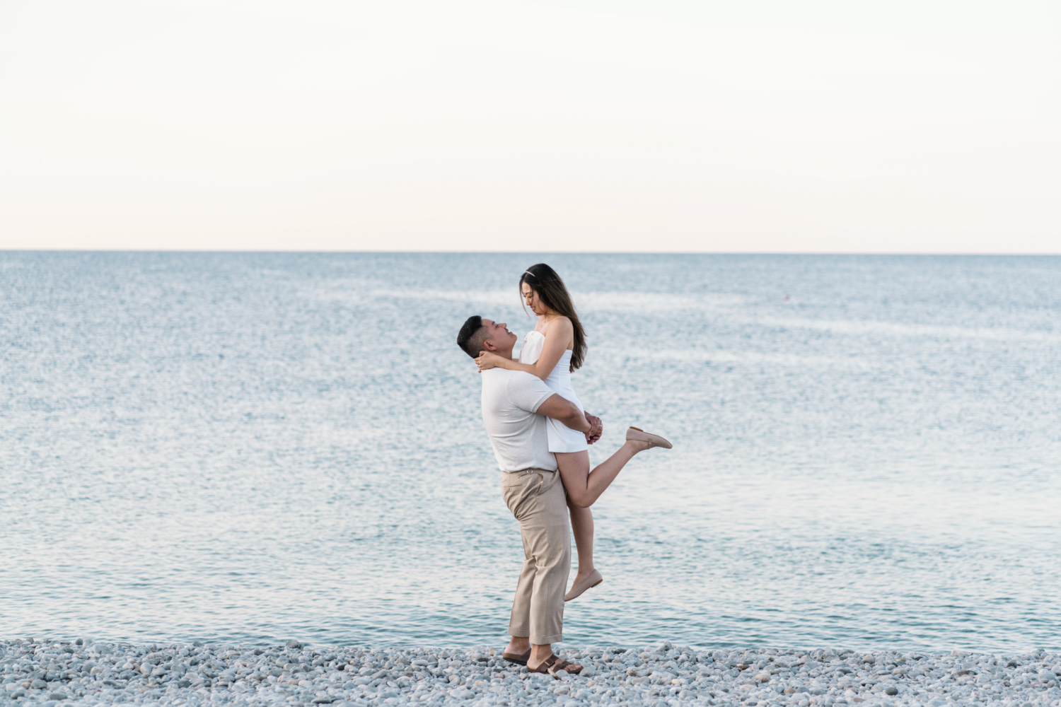 man lifts woman in air at the seaside in nice france