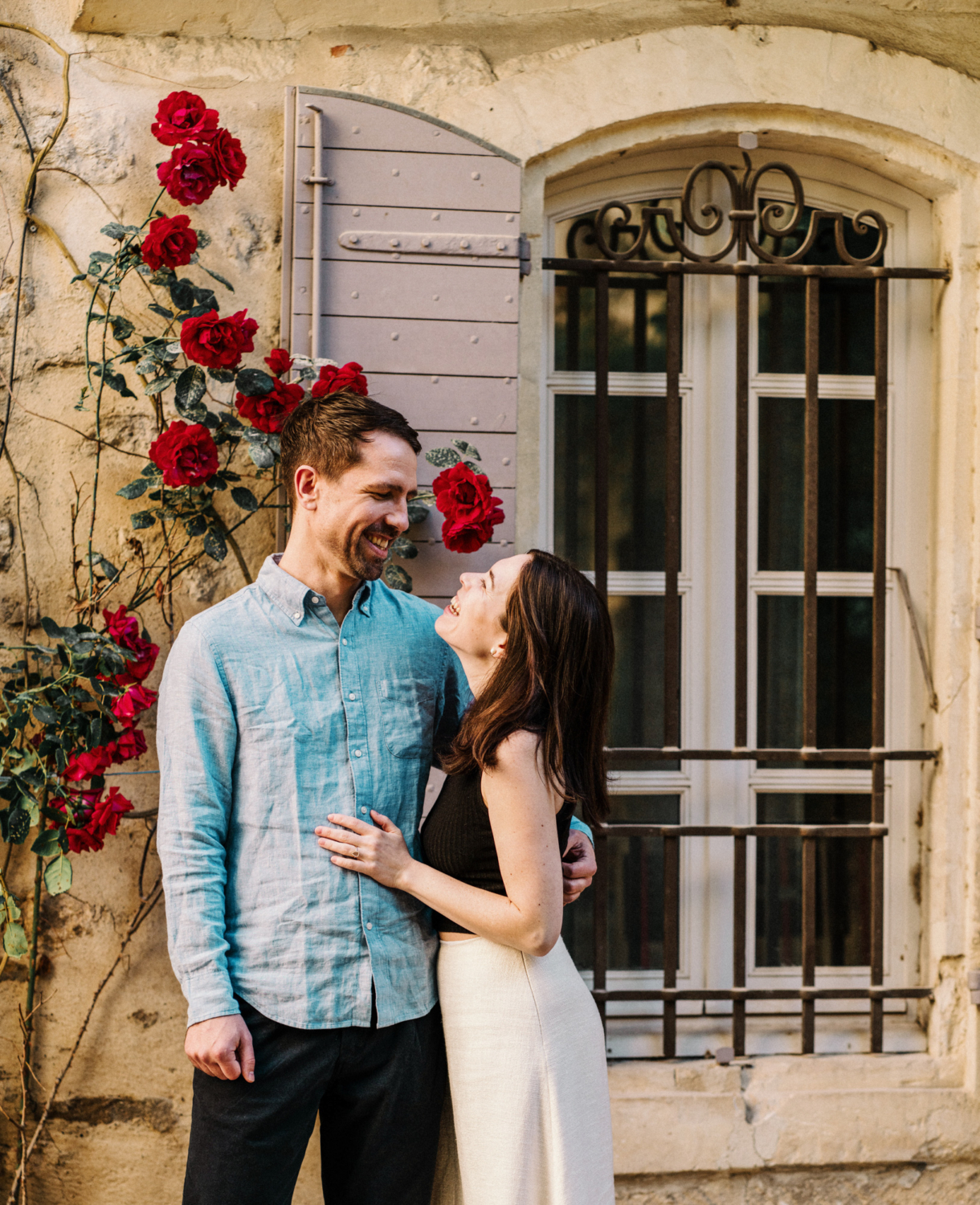 cute couple laugh near rose bush in arles