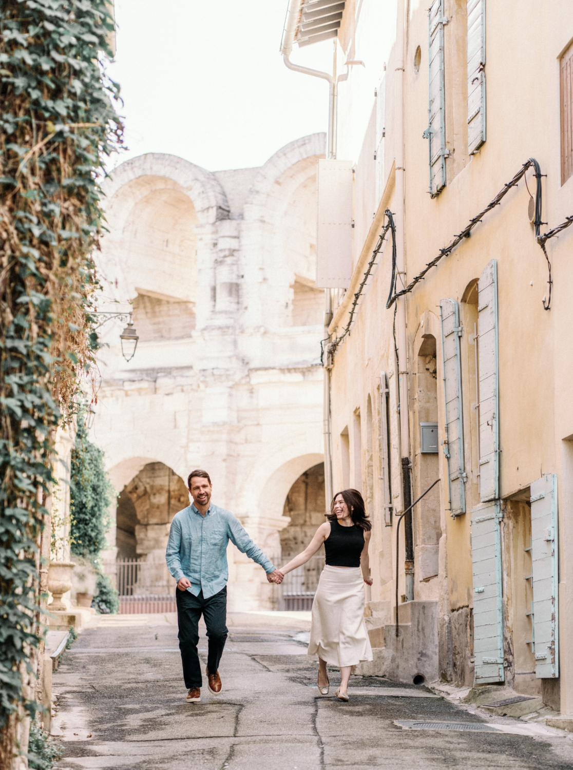 couple run with arles amphitheater in background