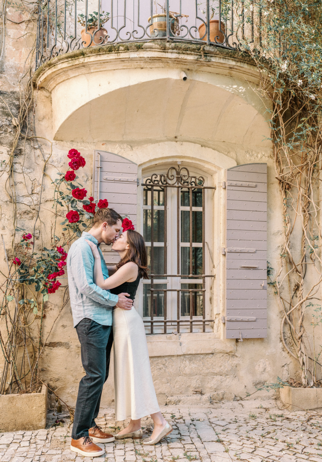 engaged couple kiss next to rose bush in arles