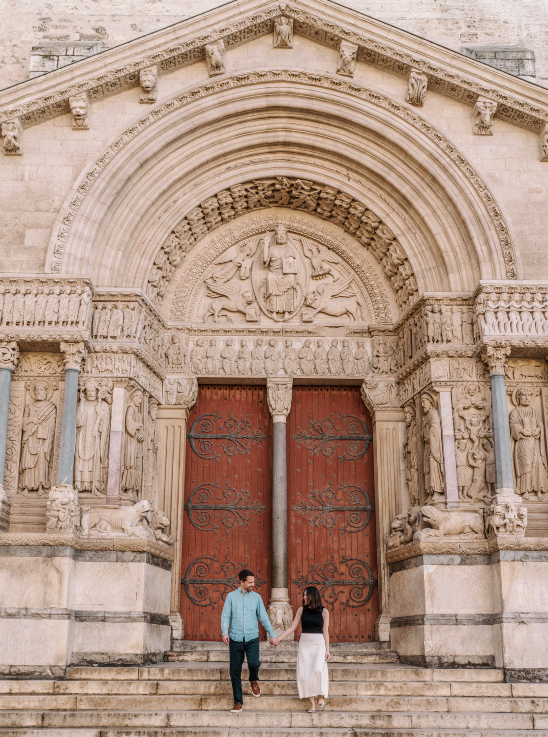 man and woman walk down steps of st trophime church in arles