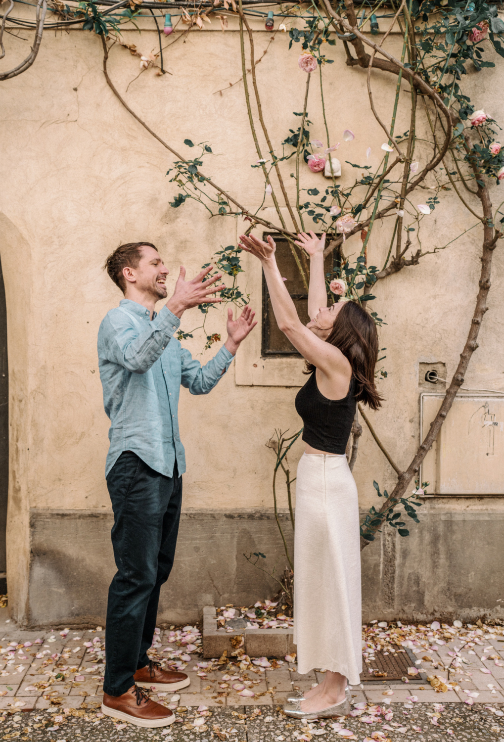 engaged couple throw rose petals in air