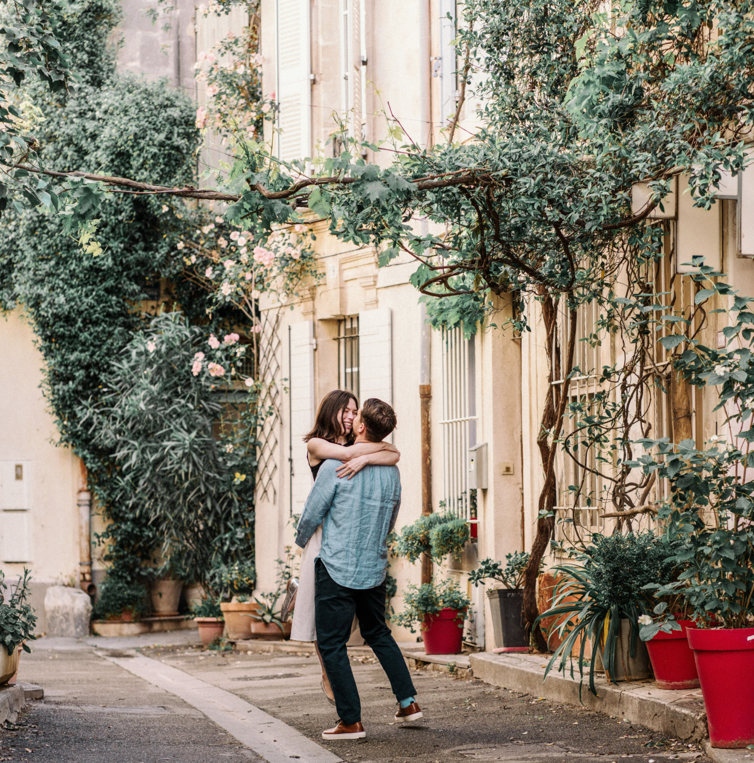 man twirls woman in arles next to rose bush