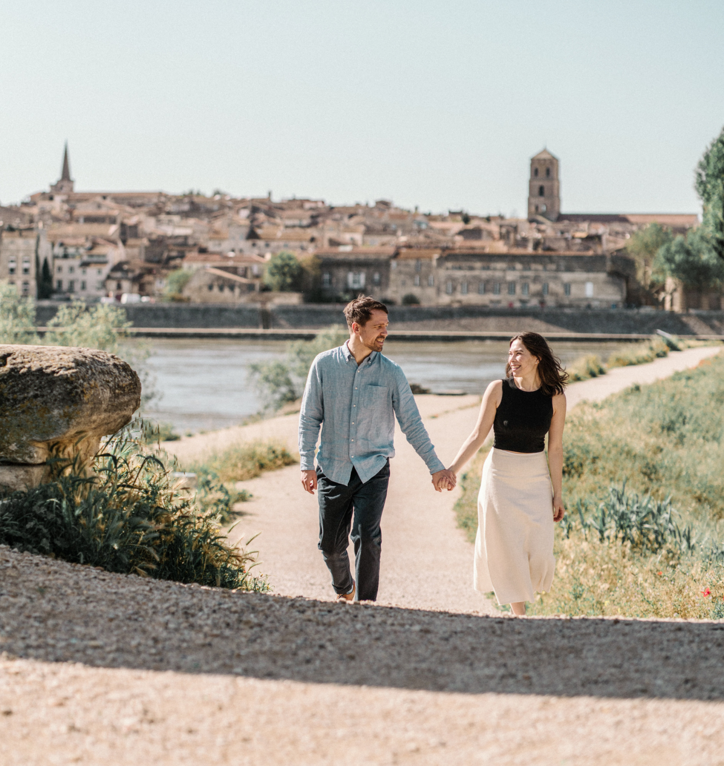 cute couple walk hand in hand with arles in background