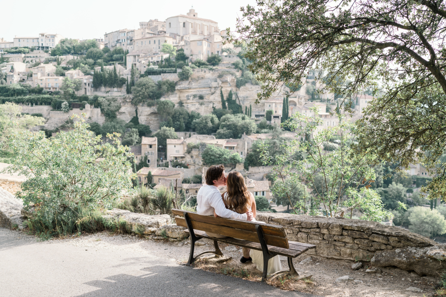 newlyweds kiss on bench in gordes france