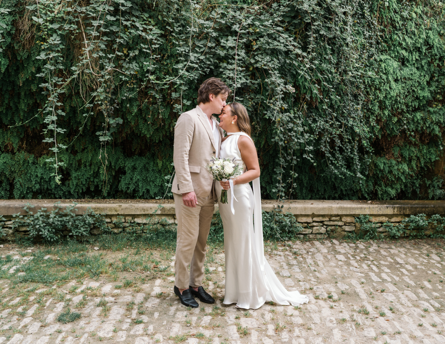 bride and groom poses in front of fern wall in gordes france