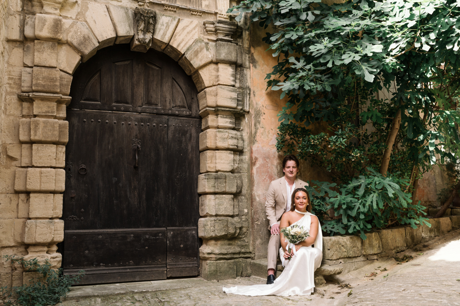 bride and groom pose next to brown door in gordes france