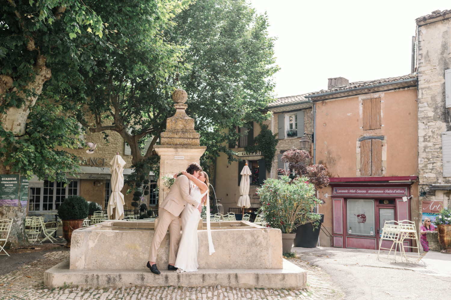 bride and groom kiss in front of old fountain in gordes france