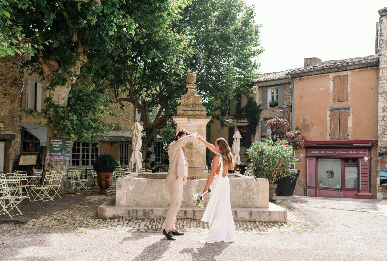 bride and groom dance in front of large fountain in gordes france