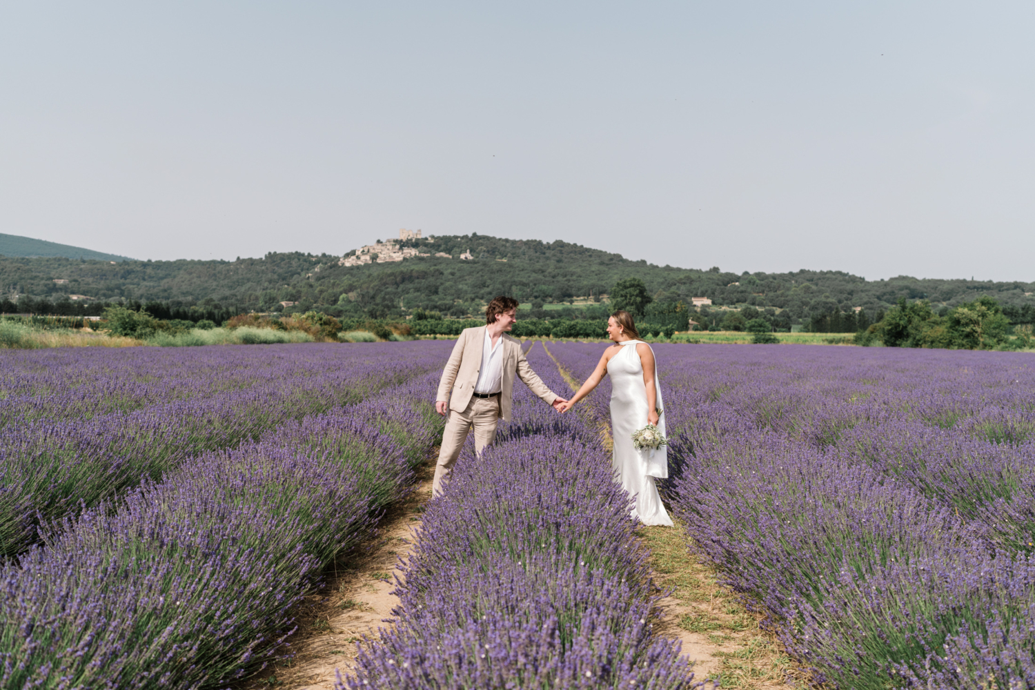 bride and groom hold hands in lavender field in provence france