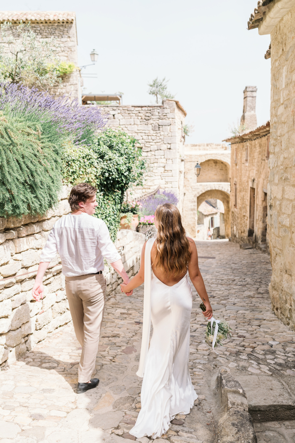 bride and groom walk hand in hand in lacoste france