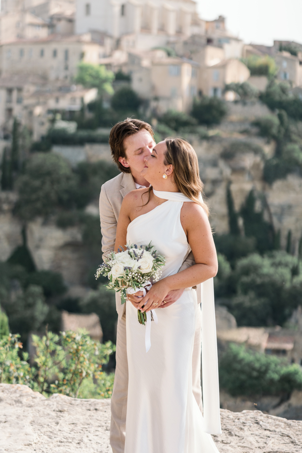 groom kisses bride on cheek in gordes france