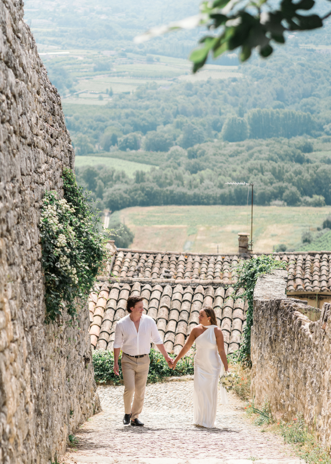 bride and groom walk hand in hand in lacoste france