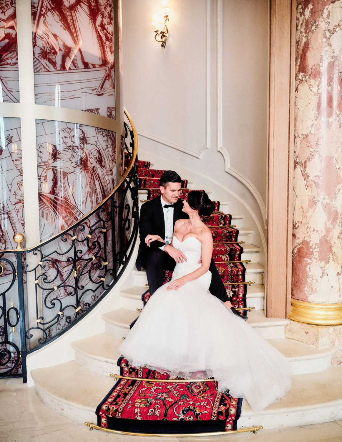 bride and groom pose on staircase at ritz hotel paris