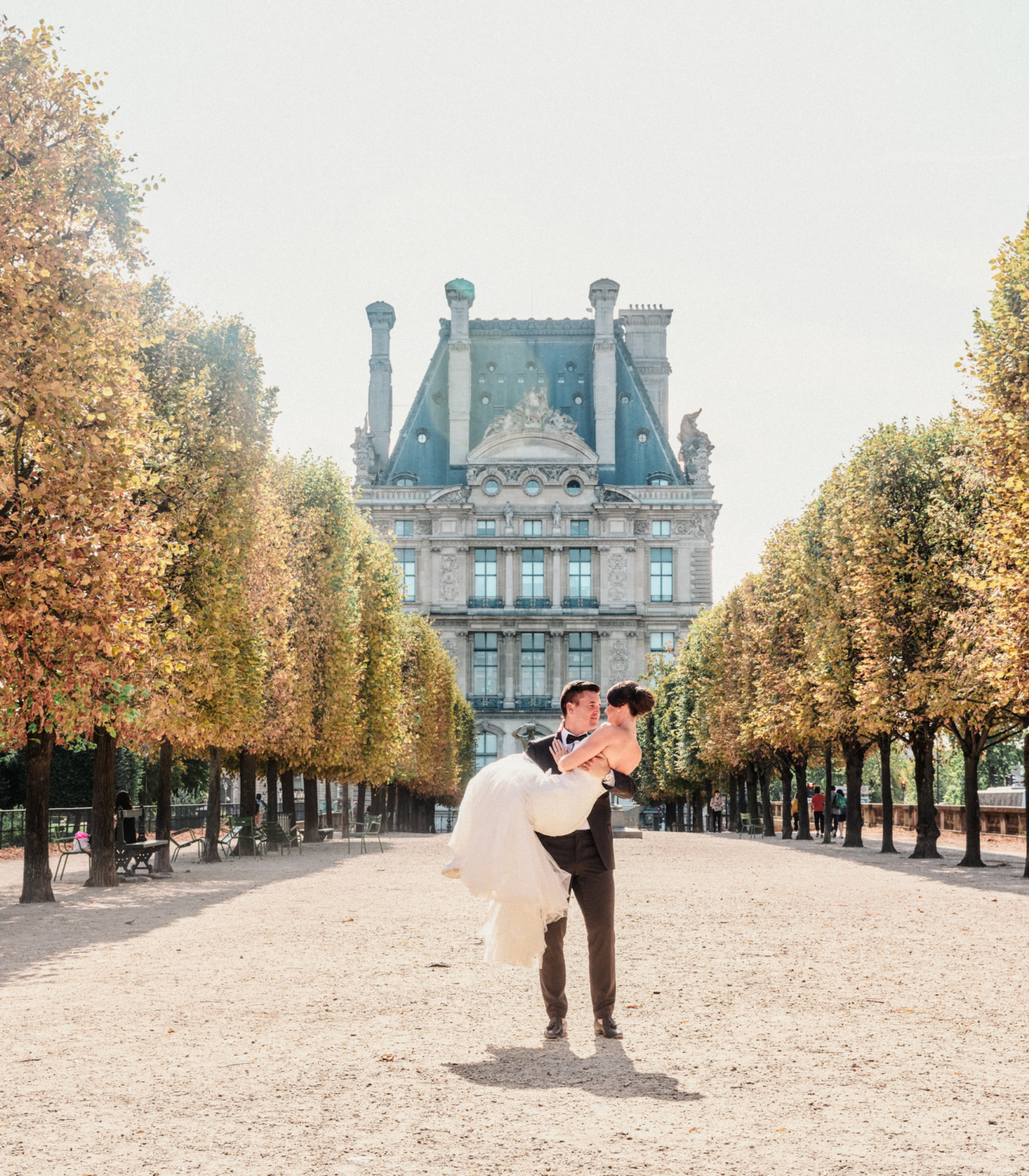 groom carries bride in tuileries gardens paris france